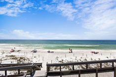 people are walking on the beach near the ocean and boardwalks in front of them