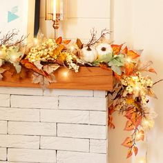 a mantel decorated with pumpkins, leaves and other autumn decorations on top of a brick fireplace