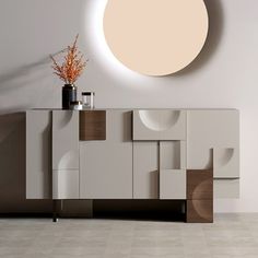 a white and brown sideboard in a room with a round light above it on the wall