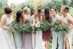 a group of women standing next to each other wearing dresses and holding flowers in their hands