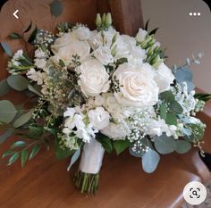 a bouquet of white flowers sitting on top of a wooden table