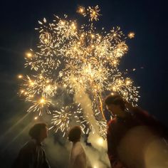 three people standing in front of a firework display