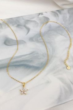 This is a fine chain necklace which is made from 18 karat gold-plated sterling silver and which features a small flower-shaped charm with five, clear-colored Marquise-cut zircon gemstones in a five-prong setting. The chain closes at the center back with a round spring clasp, and it also has an extension chain (made from larger chain links), which makes the whole thing adjustable. Delicate, classy, and a little bit feminine, this necklace will look stunning paired with anything from a boxy linen Dainty Rose Gold Flower Necklace With Delicate Chain, Dainty Rose Gold Flower Necklace, Dainty Rose Gold Flower Necklace With Clavicle Chain, Elegant Gold Charm Necklace With Flower Detail, Rose Gold Plated Necklaces With Flower Charm, Elegant Gold Charm Necklace With Flower Charm, Dainty Necklaces With Delicate Flower Chain, Rose Gold Flower Charm Necklaces, Gold Plated, Rose Gold Flower Charm Necklace Gold Plated