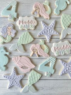 decorated cookies with mermaids and seahorses are arranged on a white table top