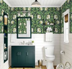 a green and white bathroom with floral wallpaper