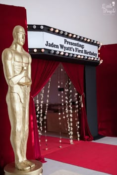 an oscar statue in front of a red curtain