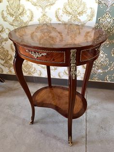 a wooden table sitting on top of a floor next to a floral wallpapered wall