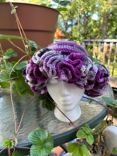 a crocheted hat sitting on top of a table next to a potted plant