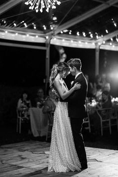 a bride and groom sharing their first dance at their wedding reception in black and white