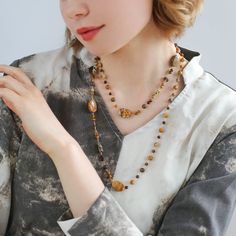 This natural stone necklace combines raw stones of different materials and shapes, creating a simple and natural original ecology with a touch of Zen aesthetics. The beautiful earth-tone design is perfect for all seasons and can be worn alone or stacked with a white fossil necklace for a stunning look. Embrace the beauty of nature with Planet Trail. Metal: 18K Recycled Gold Plated On Brass Gemstone: Tiger's Eye,Tea Crystal,Picture Stone,Other Natural Stone Length: 1040-1090mm Weight: 38g Nature-inspired Brown Necklace With Natural Variations, Nature-inspired Brown Necklaces With Natural Variations, Nature-inspired Brown Jewelry With Gemstone Beads, Elegant Adjustable Necklace With Raw Stone, Elegant Brown Necklace With Stones, Agate Necklaces With Natural Stones For Layering, Long Agate Crystal Necklace With Natural Stones, Brown Spiritual Gemstone Necklace, Nature-inspired Amber Gemstone Necklace