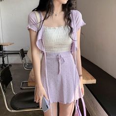 a woman holding a purple purse standing next to a table