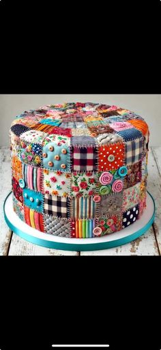 a multicolored cake sitting on top of a white plate covered in lots of fabric