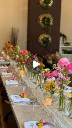 a long table with many vases filled with flowers and candles on top of it