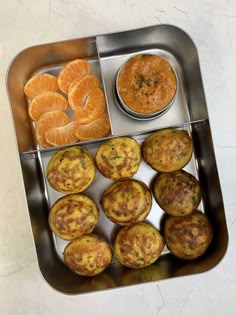 a metal tray filled with muffins and orange slices