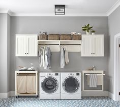 a washer and dryer in a laundry room with cabinets on the wall above them