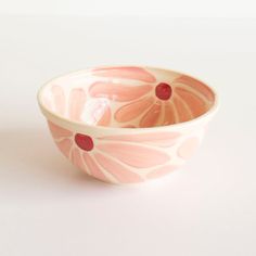 a pink and white bowl sitting on top of a white table next to a red object