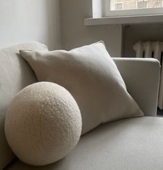 a white couch with two pillows on it and a radiator in the background