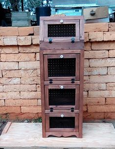 a wooden cabinet sitting on top of a piece of wood next to a brick wall