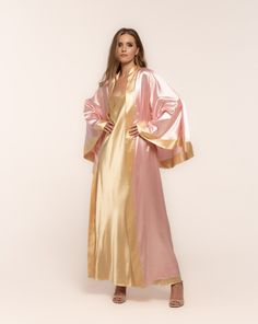 Indulge in the Kami Robe and Nightgown Set, featuring a pink robe with golden accents and a matching gold nightgown. Crafted from a luxurious silk and satin blend, this classic set promises tranquility and luxury for your moments at home. Elevate your at-home experience with this timeless ensemble. Robe:  ✓ ankle length ✓ wrap over style ✓ two sets of inside ties ✓ tie included. Nightgown:  ✓ classic style ✓ shoulder straps with ties Material Composition:  polyamide 60%, viscose 20%, polyester 1 Luxury Silk Kimono For Eid, Luxury Dola Silk Gown For Party, Luxury Pink Gown For Women, Luxury Pink Satin Robe, Luxury Pink Evening Robe, Luxury Chic Satin Kimono, Luxury Satin Chic Kimono, Luxury Silk Chiffon Gown For Women, Victorian Robe Silk Satin