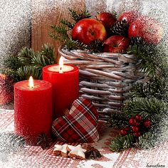 two red candles sitting next to each other in front of a basket filled with apples