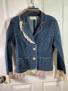 a denim jacket with lace trims hanging on a door