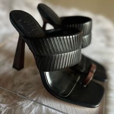 a pair of black high heeled shoes sitting on top of a bed