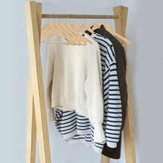 clothes are hanging on a wooden rack in front of a white wall