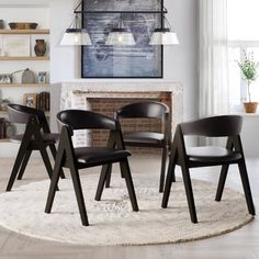 a group of four chairs sitting on top of a rug in front of a fireplace