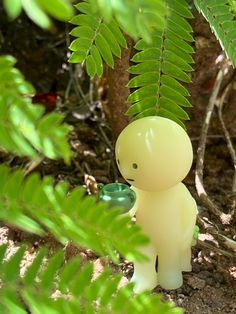 a small plastic figure standing next to a green plant