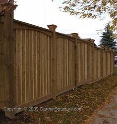 a wooden fence is shown on the side of a road with trees in the background