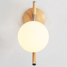 a wooden light fixture with a white ball hanging from it's side on a wall