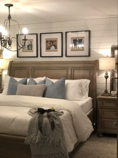 a bedroom with a bed, chandelier and pictures on the wall above it