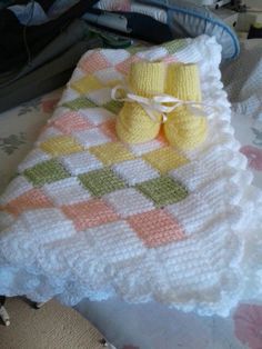 a crocheted blanket and pair of baby shoes