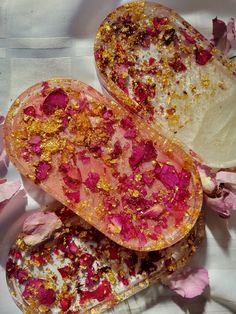 two pieces of fruit with pink and yellow sprinkles on them next to flowers