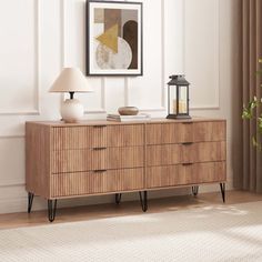 a wooden dresser with two lamps and a painting on the wall in front of it