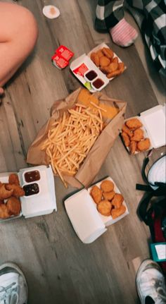 people sitting on the floor eating food and condiments from boxes in front of them