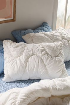 an unmade bed with blue and white pillows