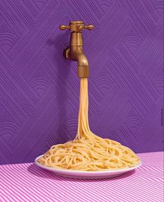 a plate of spaghetti being held by a faucet on a purple and white striped tablecloth