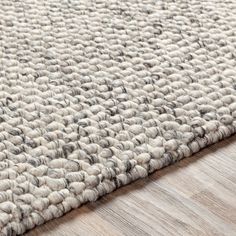 a close up view of a rug on the floor with wood floors and white carpet