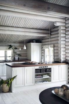 an open kitchen with white cabinets and wood flooring, along with potted plants