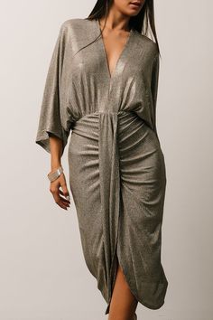 a woman is wearing a metallic dress with a wrap around the waist and heels on her feet