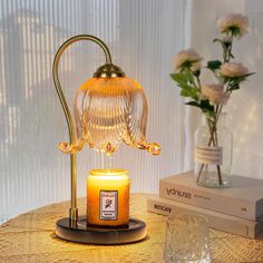 a candle is sitting on a table next to a glass vase with flowers in it