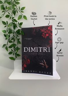 a book sitting on top of a white shelf next to a green leafy plant