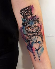 a cat wearing a top hat and holding a pocket watch tattoo on the left arm