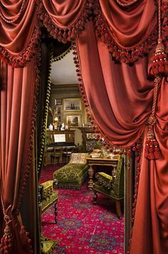 an elaborately decorated room with red drapes and pink carpeted flooring is seen through the doorway