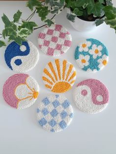 six coasters with different designs on them next to a potted plant in a vase