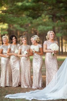 a group of women standing next to each other in front of some trees and grass