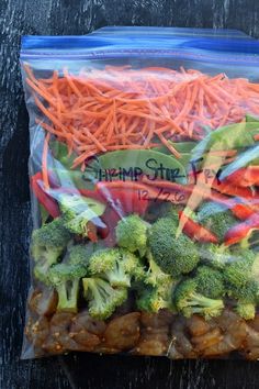 a bag filled with carrots and broccoli on top of a wooden table