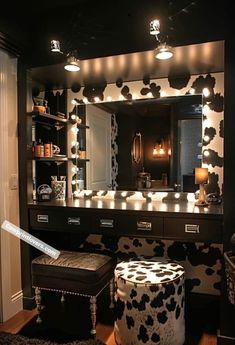 a black and white cow print vanity in a room with lights on the mirror above it