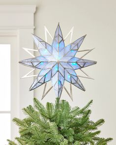 a christmas tree topper with a blue star on it's center piece and green leaves